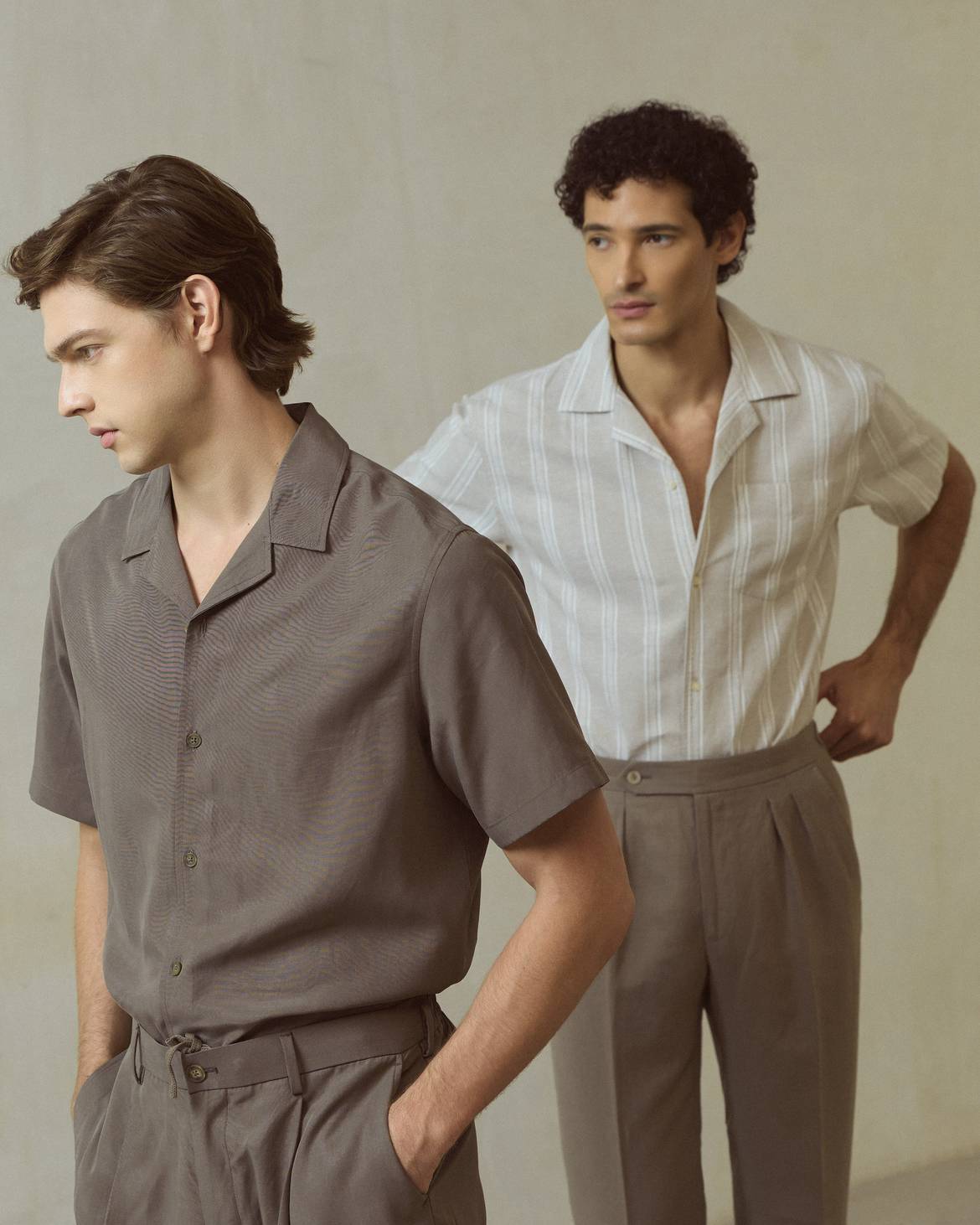 Camisa lyocell con lino manga corta caqui y camisa de lino manga corta a rayas piedra de PuroEgo, en dos modelos junto a un muro claro.