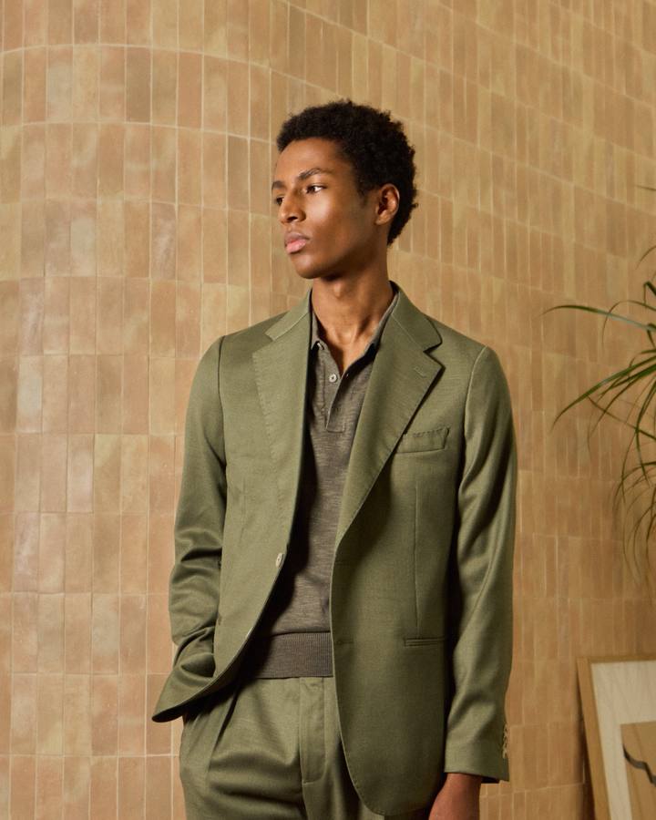 Traje desestructurado verde oliva de PuroEgo con polo de punto, junto a un muro de azulejos.
