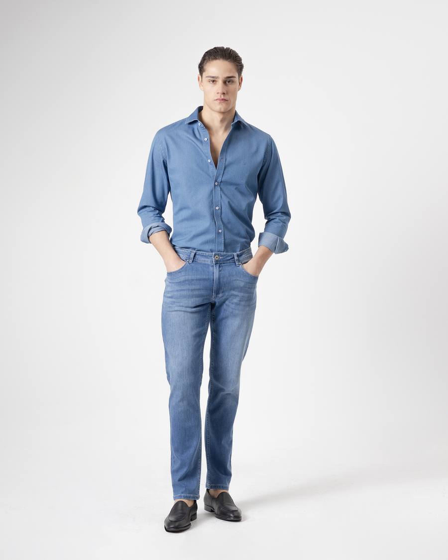 Jeans slim fit azul medio de PuroEgo de cuerpo entero, con camisa azul y mocasines, sobre fondo claro.