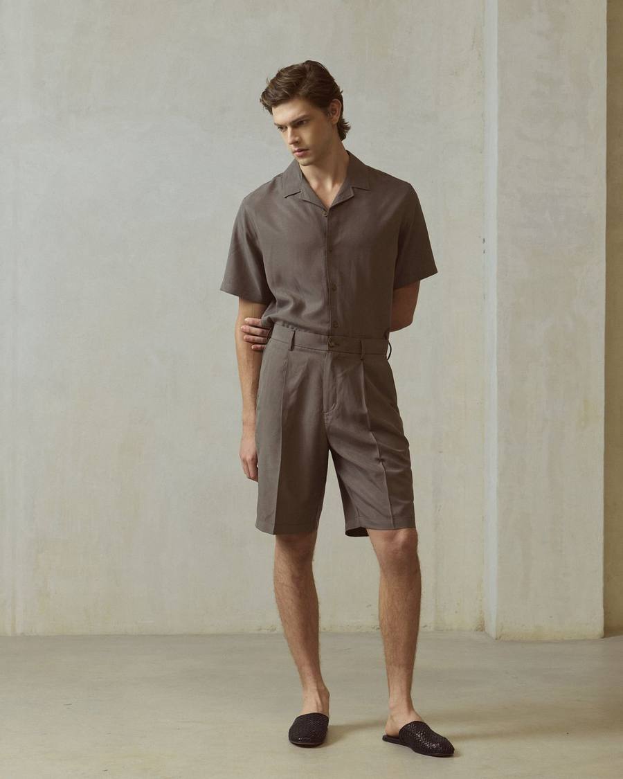 Camisa manga corta caqui y short caqui de PuroEgo, de cuerpo entero, junto a un muro claro.