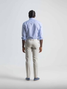 Vista posterior de pantalón chino marfil con pinzas y bolsillos traseros, combinado con camisa azul celeste de manga larga