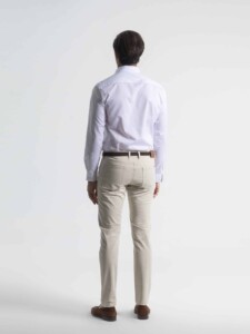 Vista de espalda de pantalón 5 bolsillos en tono arena con cinturón, combinado con camisa blanca de manga larga
