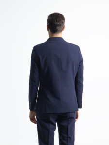 Traje 2 piezas azul marino visto de espalda: espalda de la chaqueta con costura central y botones en el puño, sobre pantalón del mismo tono.