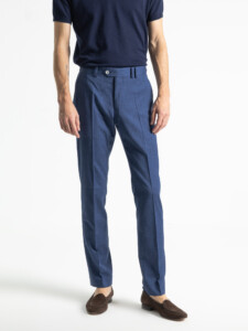 Pantalón azul del traje 2 piezas usado sin la chaqueta, de frente y de cuerpo entero hasta los mocasines, con botón de nácar en la cintura.