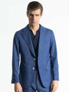 Traje 2 piezas azul de frente, chaqueta abotonada y brazos a los lados, con los botones del puño a la vista.