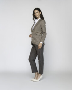 Vista lateral de blazer a cuadros beige y marrón con camisa blanca, pantalones grises y tacones, modelo Formentera