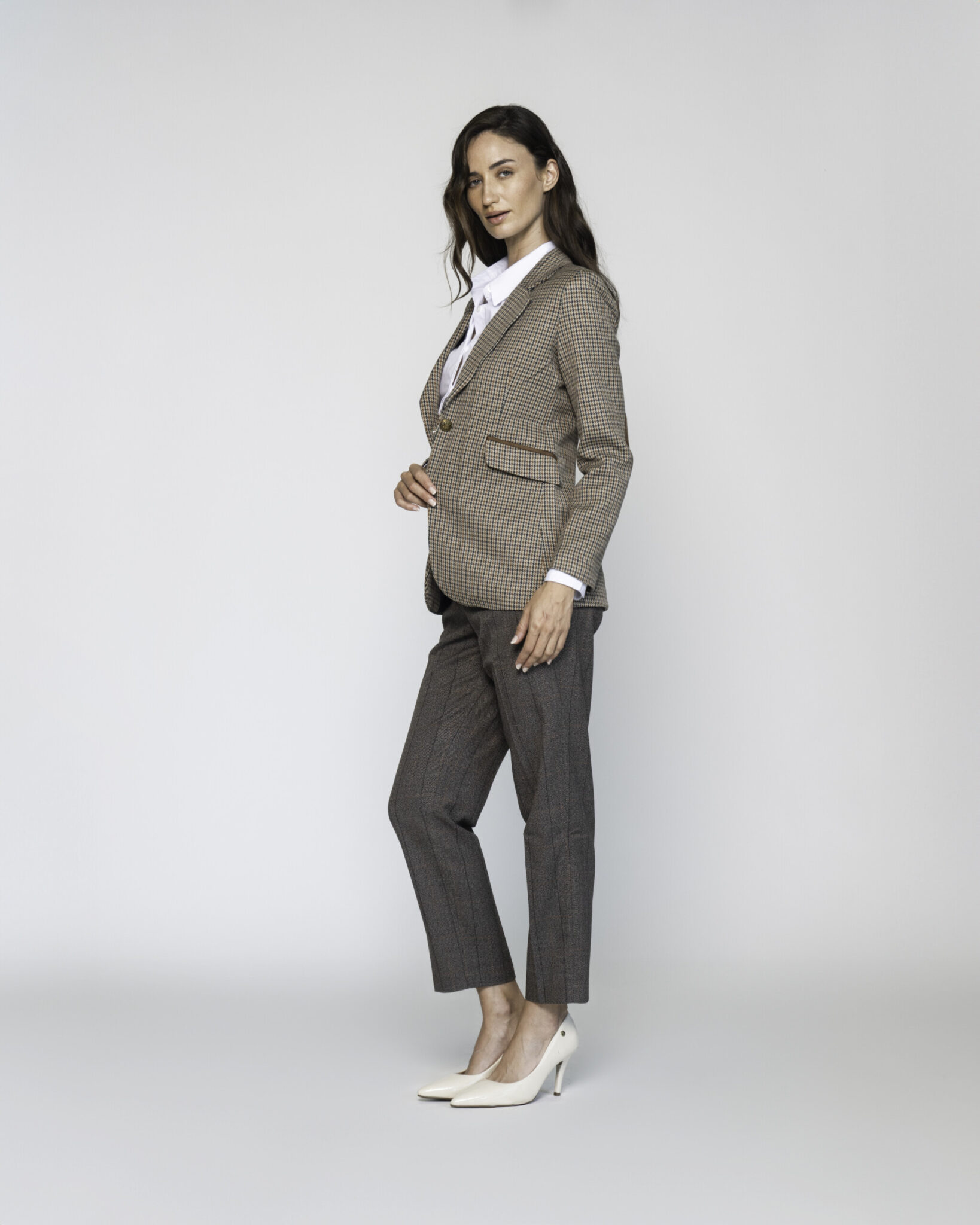 Vista lateral de blazer a cuadros beige y marrón con camisa blanca, pantalones grises y tacones, modelo Formentera