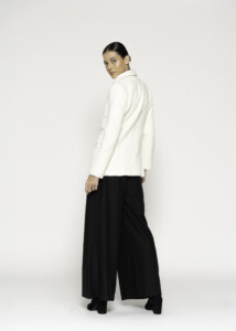 Vista trasera de blazer blanco cruzado con textura tweed, combinado con pantalón palazzo negro amplio, modelo Formentera