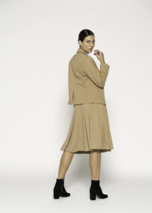 Vista de perfil de blazer camel con bordado visible, solapa y bolsillo lateral, combinado con falda plisada, modelo Formentera