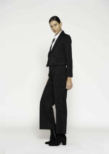 Vista lateral de blazer negro con rayas finas y doble botonadura, combinado con pantalón a juego y camisa blanca