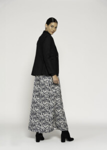 Vista lateral del blazer negro de solapas con corte relajado, combinado con falda estampada blanco y negro, modelo Formentera
