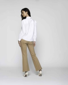 Vista de espalda de blusa blanca con cuello camisero y manga larga con puños ajustados, combinada con pantalón camel