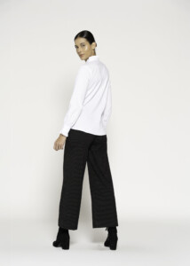 Vista de espalda de blusa blanca con cuello mao, manga larga y pantalones a rayas negras, modelo Formentera