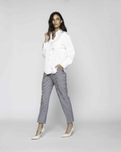 Vista completa de cuerpo entero con camisa blanca de popelín y pantalón de cuadros vichy, mano en cuello, modelo Formentera