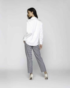 Vista de espalda de blusa blanca con cuello clásico y manga larga, combinada con pantalón de cuadros y zapatos blancos