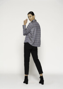 Vista de tres cuartos trasera de blusa con estampado geométrico en tonos azul y gris, cuello alto, combinada con pantalón negro
