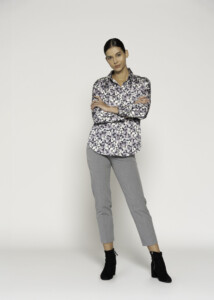 Vista completa de blusa estampada con motivos geométricos en rosa, gris y blanco, combinada con pantalón gris y botines negros