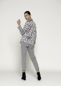 Vista de tres cuartos de espalda mostrando blusa con estampado rosa, gris y blanco, cuello clásico y manga larga, modelo Formentera