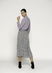 Vista completa de espalda en tres cuartos mostrando blusa lila con cuello clásico y falda estampada midi con botines negros