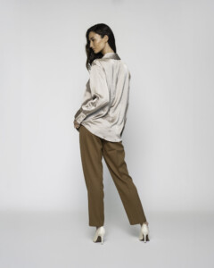 Vista trasera de blusa satinada beige con cuello camisero y corte oversize, combinada con pantalón caqui, modelo Formentera