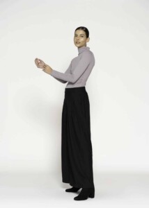 Vista de perfil del body lila con cuello alto y manga larga, combinado con pantalón negro amplio, modelo Formentera