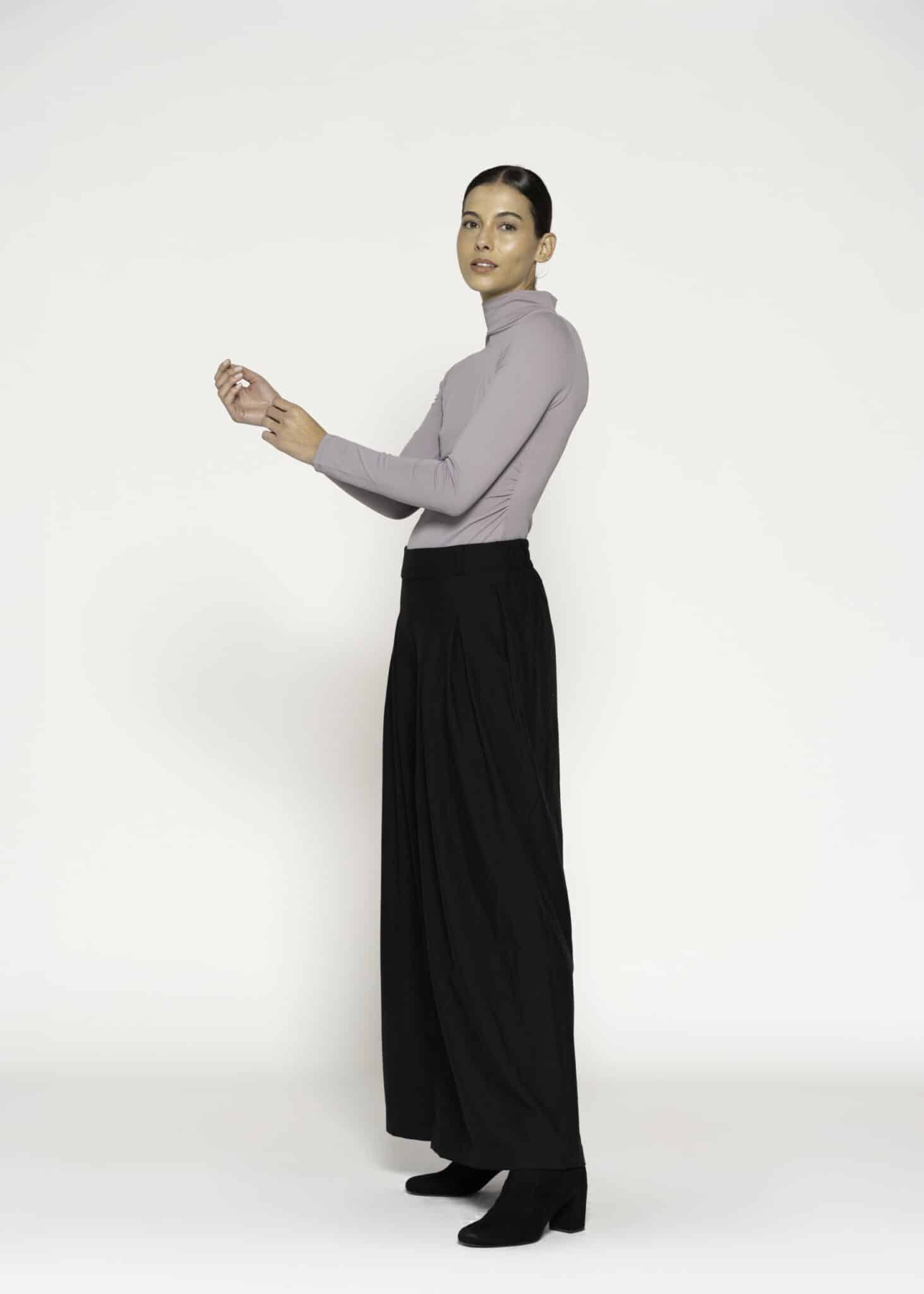 Vista de perfil del body lila con cuello alto y manga larga, combinado con pantalón negro amplio, modelo Formentera