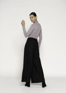 Vista de tres cuartos posterior del body lila con cuello alto, manga larga ajustada, combinado con pantalón palazzo negro