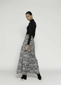 Vista lateral del body negro de cuello alto con manga larga, combinado con falda larga estampada blanco y negro