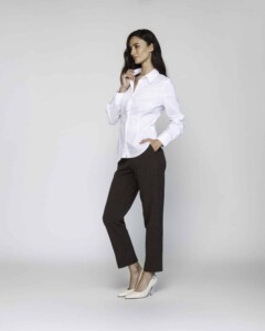 Vista lateral de camisa blanca con cuello clásico y pinzas, combinada con pantalón oscuro y stilettos, modelo Formentera