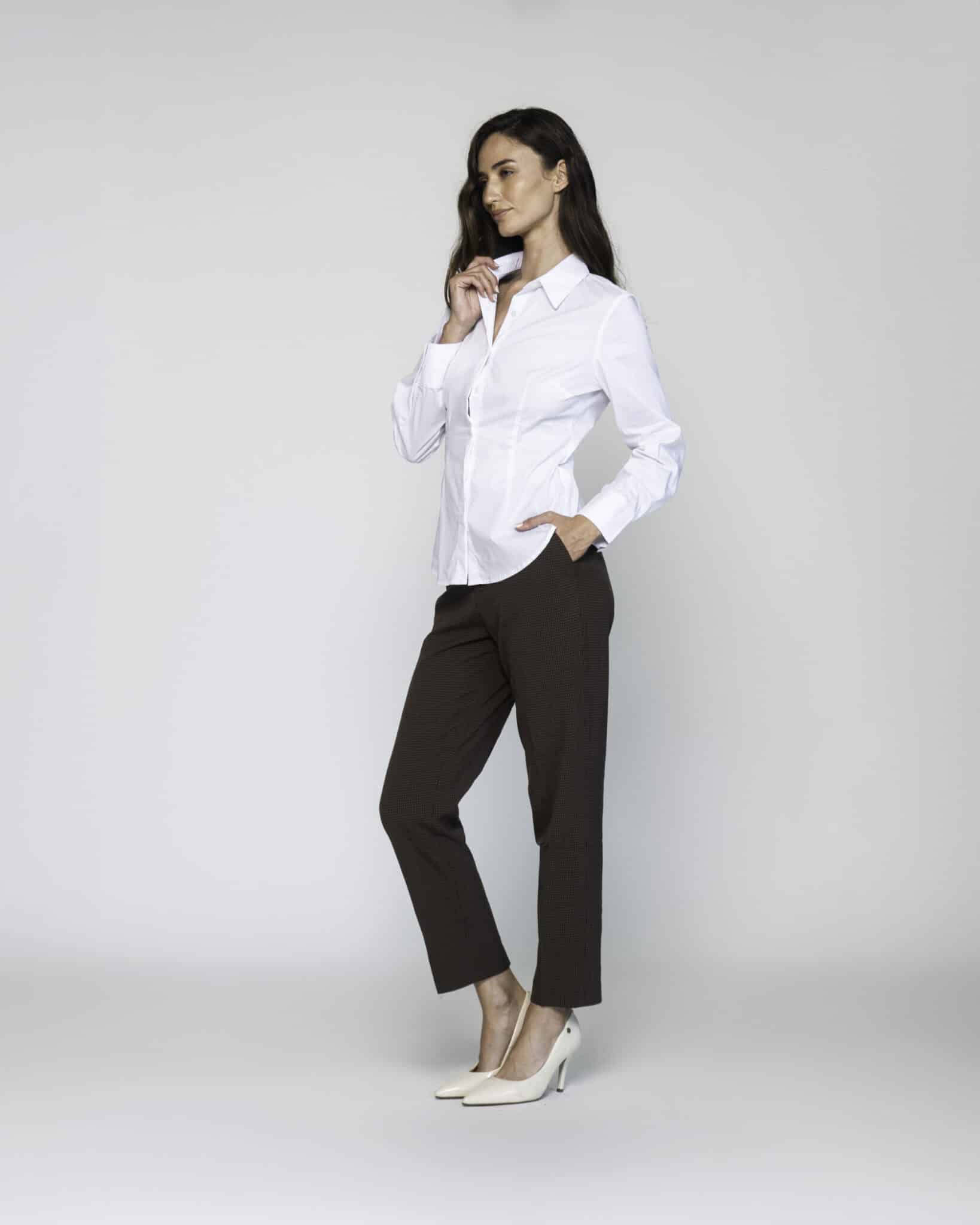 Vista lateral de camisa blanca con cuello clásico y pinzas, combinada con pantalón oscuro y stilettos, modelo Formentera