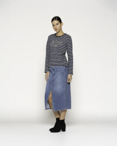 Vista completa de camiseta a rayas azul marino y blancas con texto bordado al pecho, combinada con falda denim y botines negros