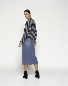 Vista de espalda de camiseta a rayas horizontales azul marino y blancas de manga larga, combinada con falda denim midi