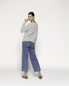 Vista trasera de camiseta a rayas blancas y negras con jeans culotte azul, modelo mirando sobre el hombro
