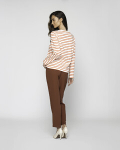 Vista de espalda de camiseta a rayas horizontales blancas y naranjas con manga larga, combinada con pantalón marrón