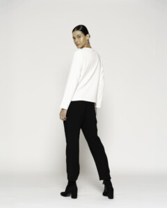 Vista de espalda de camiseta blanca manga larga con pantalón negro, modelo gira sobre el hombro, modelo Formentera