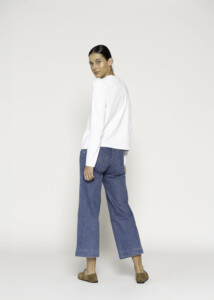Vista posterior de tres cuartos mostrando camiseta blanca manga larga con jeans de corte amplio, modelo Formentera