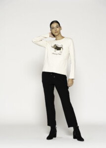 Vista completa del conjunto: camiseta cruda con estampado de perro y pantalones negros, en pose de tres cuartos frontal