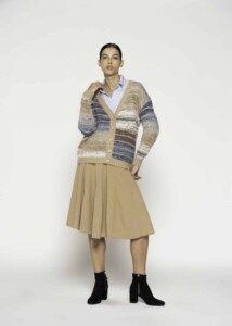 Vista completa de cardigan a rayas beige y azul con camisa celeste debajo y falda plisada camel, modelo Formentera