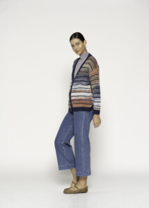 Vista lateral de cardigan tejido a rayas horizontales en tonos azul, beige, naranja y blanco, con cuello tortuga lila debajo