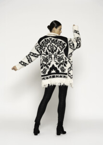 Vista de espalda del cardigan tejido crudo con diseño jacquard negro geométrico y flecos en el bajo, modelo Formentera