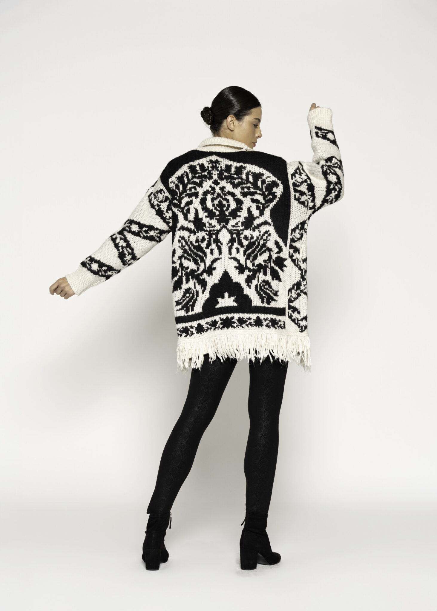 Vista de espalda del cardigan tejido crudo con diseño jacquard negro geométrico y flecos en el bajo, modelo Formentera