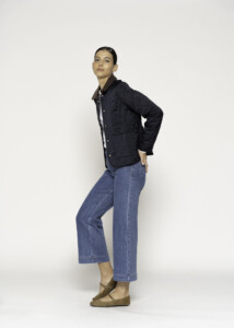 Vista lateral de chaqueta acolchada azul marino con botones frontales y cuello contrastante, combinada con jeans culotte