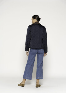 Vista trasera de chaqueta acolchada azul marino con patrón romboidal, combinada con jeans acampanados, modelo Formentera