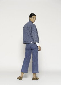 Vista trasera de chaqueta denim azul con tachas plateadas distribuidas por la espalda, sobre jeans culotte modelo Formentera.