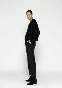 Vista lateral de chaqueta tejida negra con textura bouclé, se aprecia manga larga y caída oversize del tejido, modelo Formentera