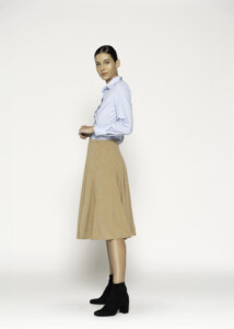 Vista lateral de falda midi camel con pliegues y camisa lila, se aprecia caída y volumen del diseño modelo Formentera