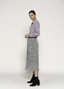 Vista lateral de falda midi con estampado animal en blanco y negro, cintura elástica, combinada con camisa lila y botines negros