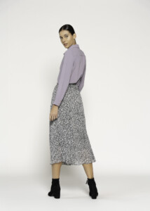 Vista de espalda de falda midi plisada con estampado animal print en blanco y negro, combinada con camisa lila, modelo Formentera