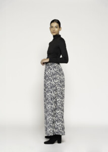 Vista lateral de tres cuartos del pantalón ancho con estampado abstracto blanco y negro, combinado con top negro de cuello alto