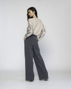 Vista trasera de pantalón ancho gris con pinzas, combinado con suéter beige de mangas con lentejuelas, modelo Formentera